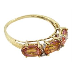 9ct gold three stone azotic topaz ring, with four diamond accents set between, hallmarked 