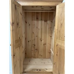 Waxed pine double wardrobe, fitted with two doors, opening to reveal interior fitted for hanging over two drawers, raised on a plinth base