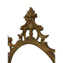 Ornate oval gilt frame wall mirror, the moulded frame decorated with scrolled cartouche and trailing foliage, with shell scalloped edge, plain glass plate