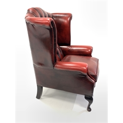 20th century wingback armchair, upholstered in deep buttoned and studded oxblood leather, raised on cabriole front supports, W82cm