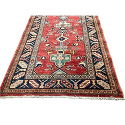 Persian design red ground rug, the field decorated with a central pole medallion comprising of urns and floral patterns, the indigo border with geometric repeating designs