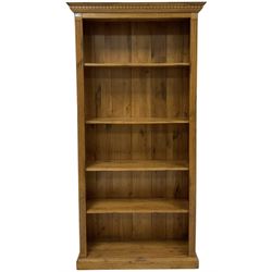 Oak bookcase, the projecting dentil cornice over four adjustable shelves with reeded sides, raised on a plinth base 