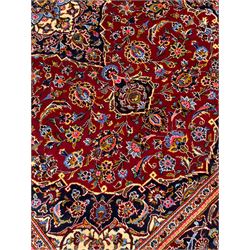 Small Persian Kashan red ground rug, central indigo blue ground medallion and spandrels, all-over floral design, the field decorated with interlacing foliage and stylised flower heads, multi-band border with repeating design decorated with plant motifs