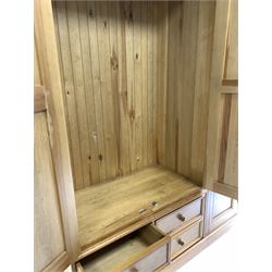 Polished pine triple wardrobe, full length panel door enclosing interior fitted for hanging, flanked by two further cupboard doors, over two short and one long drawer 